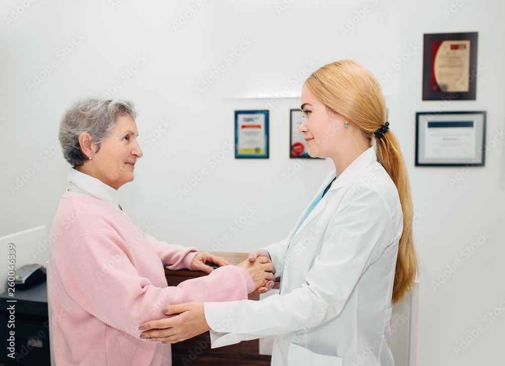 Fototapeta premium doctor comforting senior woman during a checkup at clinic