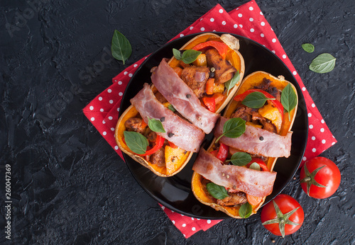 Stuffed pumpkin Butternut meat and vegetables wrapped in bacon on black slate background. Copy space. Top view
