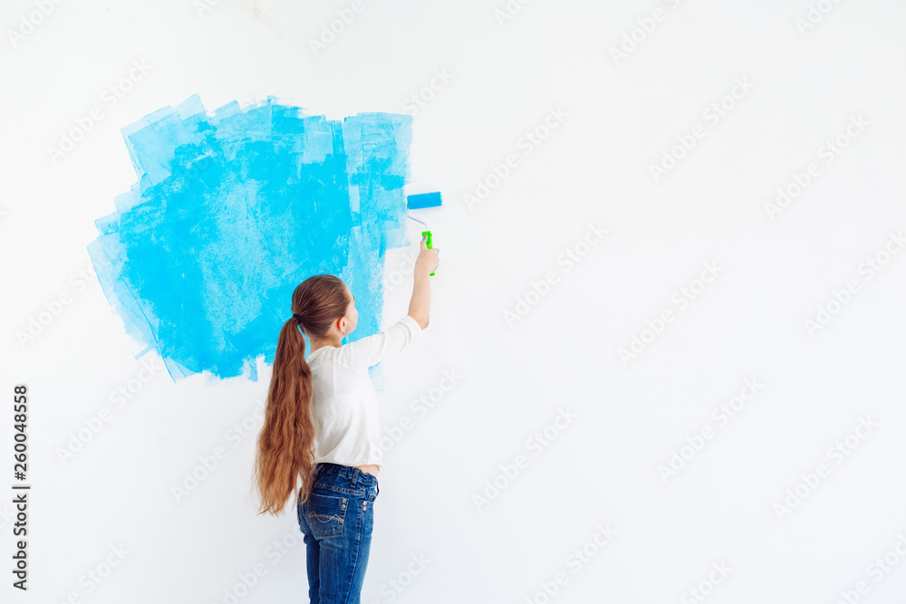 Repair in the apartment. Happy child girl paints the wall with blue paint, Repair in the apartment. Happy child girl paints the wall with blue paint,
