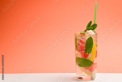 Obraz Czerwony świeży napój z lodem, grejpfrutem i mennicą na pomarańczowym tle. Miejsce na tekst lub projekt.