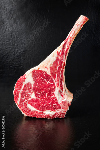 Tableau sur toile Raw dry aged wagyu tomahawk steak on black background with copy space