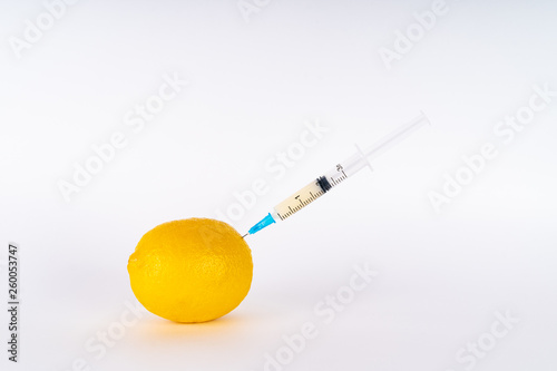 Injection of a lemon with a syringe. Antibiotic or GMO. Genetically modified fruit on white background