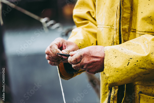Mains d'un pêcheur en train de réparer son filet