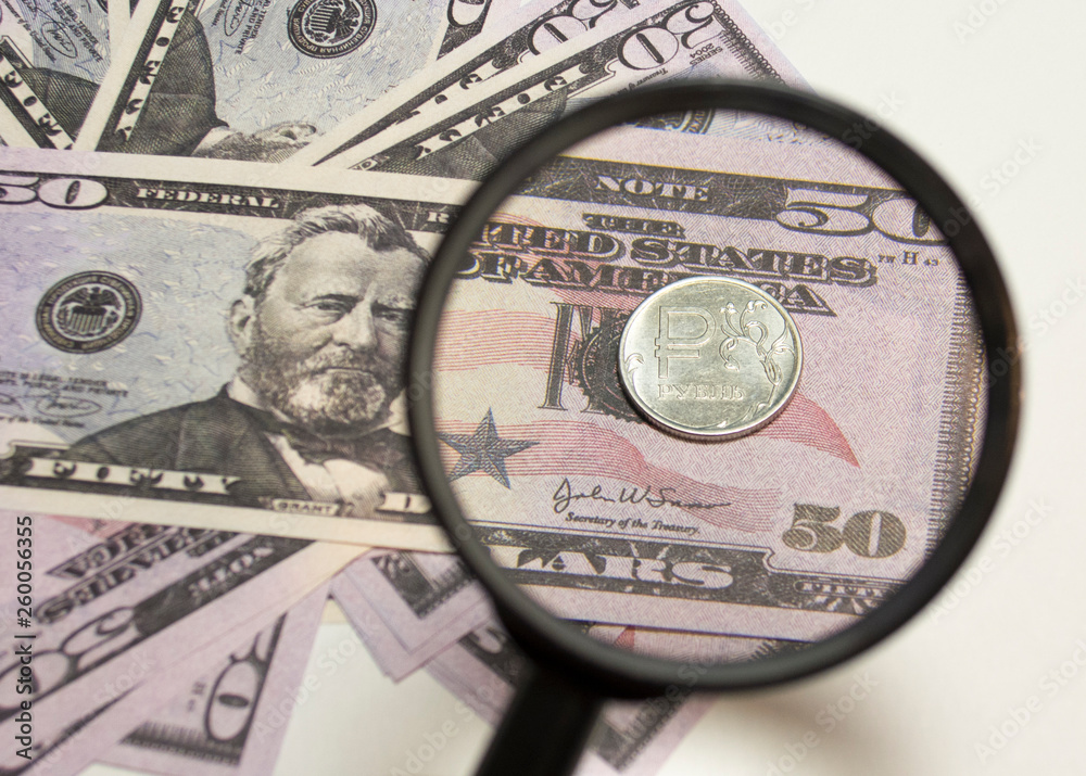 Coin of ruble with a magnifier on the background of dollars. Magnifier and money. Business concept background. Coin of ruble with a magnifier on the background of dollars. Magnifier and money. Business concept background.