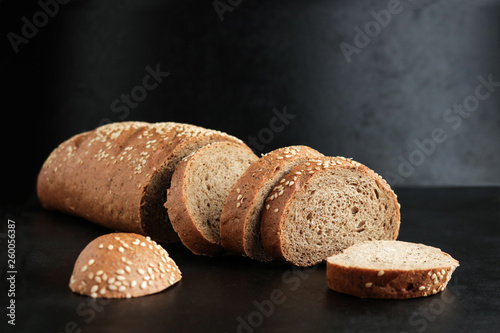 sliced homemade brown rye bread with sesame seeds on black background
