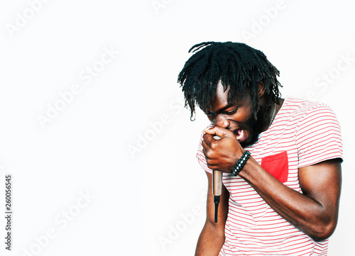 young handsome african american boy singing emotional with microphone isolated on white background, in motion gesturing smiling close up. karaoke singer