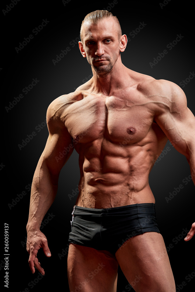 Athletic man posing. Photo of man with perfect physique on black background. Strength and motivation Athletic man posing. Photo of man with perfect physique on black background. Strength and motivation