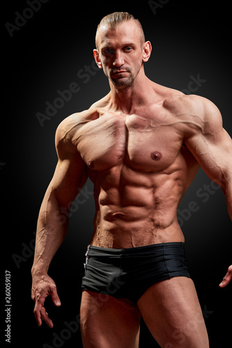 Athletic man posing. Photo of man with perfect physique on black background. Strength and motivation