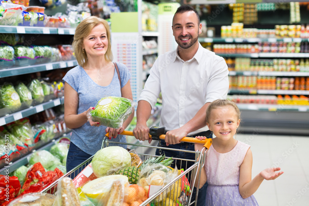 Smiling parents with child choosing lettuce