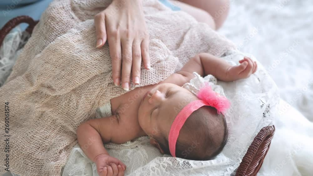 Mother take care of Asian female newborn baby lying in bed and sunlight in the morning. Cute little girl three weeks old. Healthcare, love, relationship concept Mother take care of Asian female newborn baby lying in bed and sunlight in the morning. Cute little girl three weeks old. Healthcare, love, relationship concept