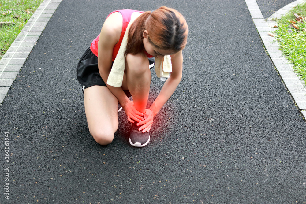 Young Asian fitness woman runner suffering from broken twisted ankle. Running injury accident concept.