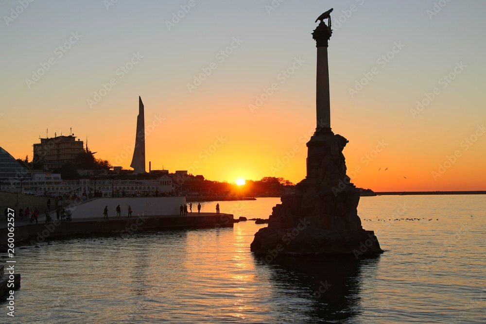 Embankment in the center of Sevastopol during sunset. In the rays of the setting sun, the Monument to the Sunken Ships and Monument to the Bayonet and Sail are visible.