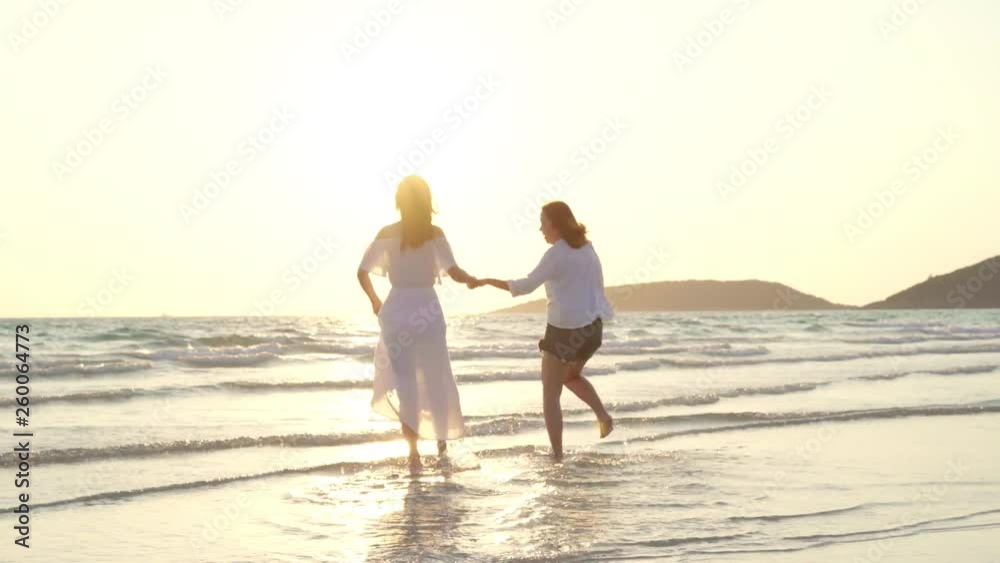 Young Asian lesbian couple running on beach. Beautiful women friends happy relax having fun on beach near sea when sunset in evening. Lifestyle lesbian couple travel on beach concept. Young Asian lesbian couple running on beach. Beautiful women friends happy relax having fun on beach near sea when sunset in evening. Lifestyle lesbian couple travel on beach concept.