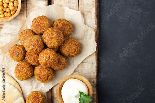 Vegetarian chickpeas falafel balls on wooden rustic board. Traditional Middle Eastern and arabian food. Dark background. Copy space.