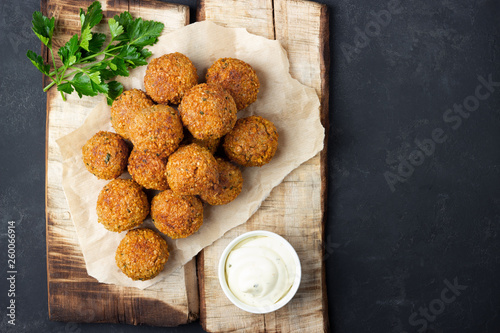 Vegetarian chickpeas falafel balls on wooden rustic board. Traditional Middle Eastern and arabian food. Dark background. Copy space.