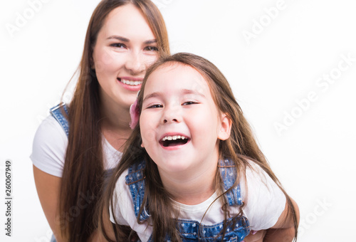 Motherhood, family and relationship concept - Happy mother and little daughter having fun on white background