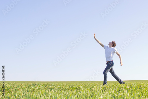 teenager running through a field of green wheat