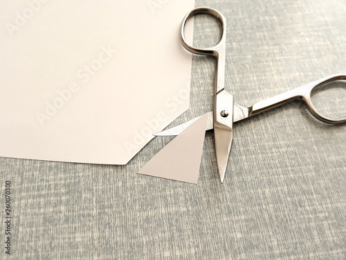 Cutting corners idiom Briticism hand takes sheet of paper and cutting corners by scissors doing something so easily and cheaply as possible 