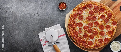 Obraz  z motywem pepperoni pizza on wooden serving board shot top down with copy space composition