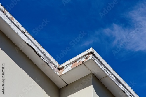 Fotografi Roof repair and maintenance concept image consisting of old rotting fascia boards and a blue sky background