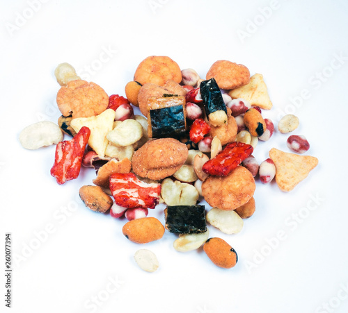 Mix of Asian snack on white background. Including Nori Maki Arare rice crackers in seaweed, glaze peanuts and fried crackers. Close up.