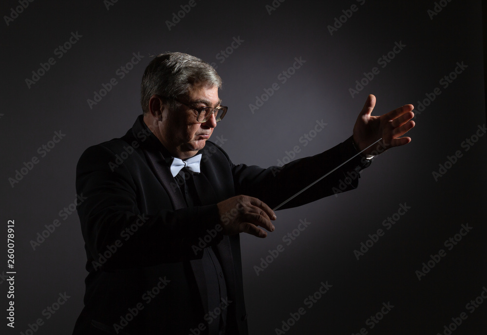 Emotional portrait of the conductor gesticulating with his hands on a dark background. Emotional portrait of the conductor gesticulating with his hands on a dark background.