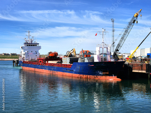 Coastal cargo ship discharging cargo at harbour berth facilities.