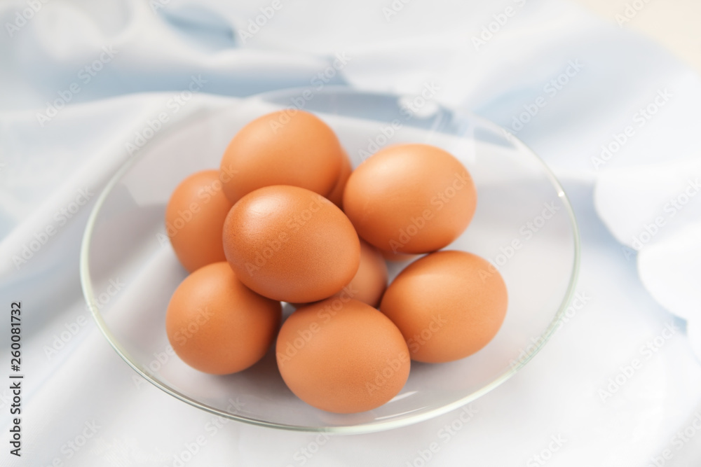 Hens eggs in the glass plate on the blue table-cloth Hens eggs in the glass plate on the blue table-cloth