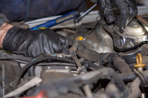 Car mechanic repairs diesel engine. Old and dirty car engine with car mechanics hands. Car repairing concept in the garage workshop.