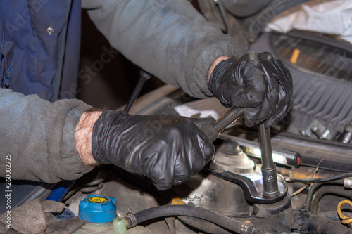 Car mechanic repairs diesel engine. Old and dirty car engine with car mechanics hands. Car repairing concept in the garage workshop.