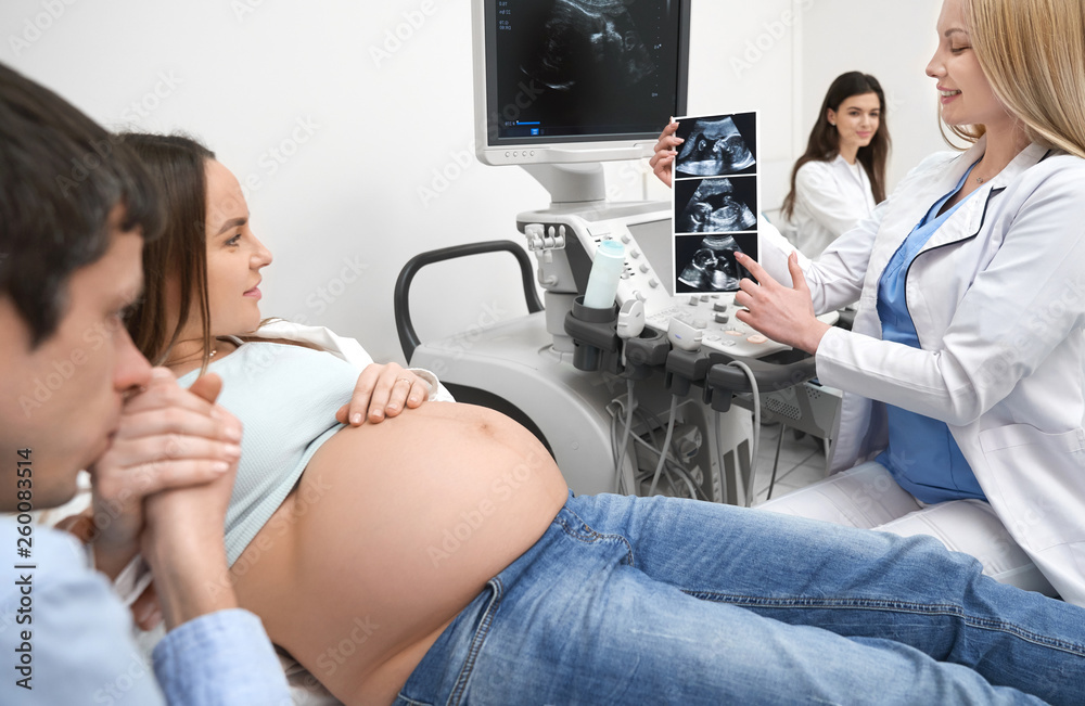 Obraz premium Future father kissing hand of pregnant wife in clinic