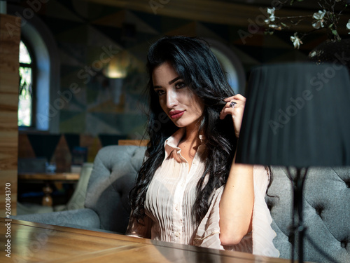 beautiful brunette girl sitting at a table in a restaurant and looking at the camera