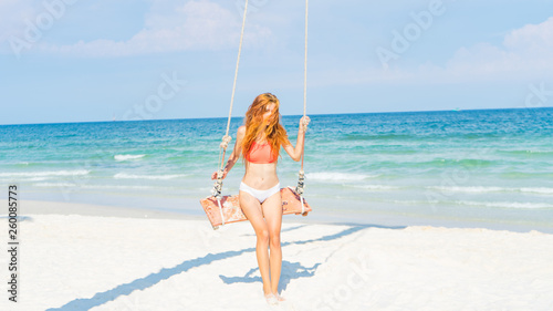 Red haired girl in bikini swinging on the beautifyl beach with white sand and crystal water in Phu quoc island Vietnam ,travel concept
