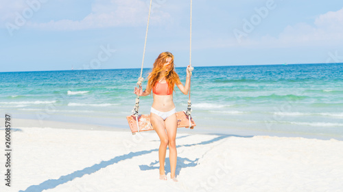 Red haired girl in bikini swinging on the beautifyl beach with white sand and crystal water in Phu quoc island Vietnam ,travel concept