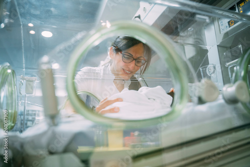 Female doctor examining newborn baby in incubator photo