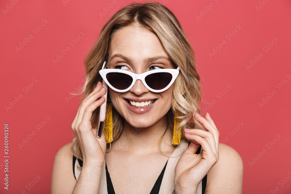 Amazing young woman posing isolated over red coral background talking by mobile phone. Amazing young woman posing isolated over red coral background talking by mobile phone.