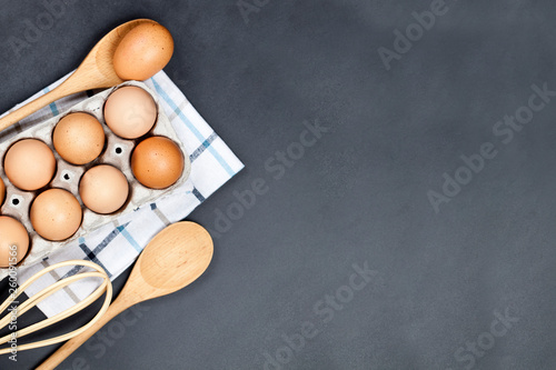 Fresh eggs and kitchen utensil on backboard background. photo