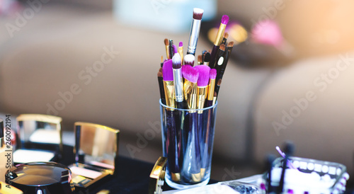 Picture with make up brushes of professional beautician. Bridal set of cosmetic products lie on table. Makeup kit for wedding or fashion events. Multi-colored lipstick collection.