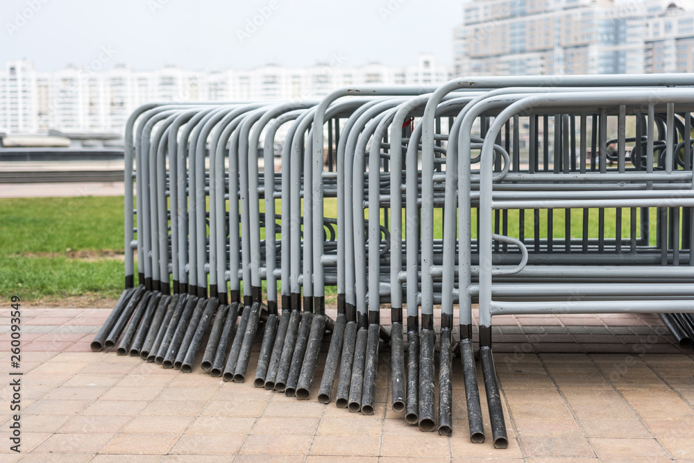 Many movable metal fences stacked. Portable metal grilles of light gray color for the obstruction of the territory and organization of the queue for the event