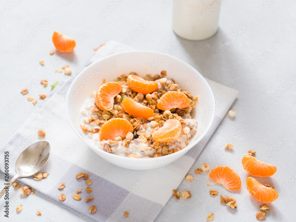 Healthy breakfast. Baked muesli with tropical fruits, fresh tangerines and yogurt on white background Healthy breakfast. Baked muesli with tropical fruits, fresh tangerines and yogurt on white background