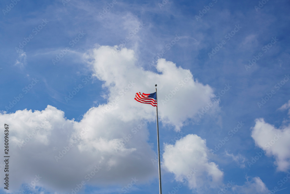 American flag swinging in a blue sky with clouds scene