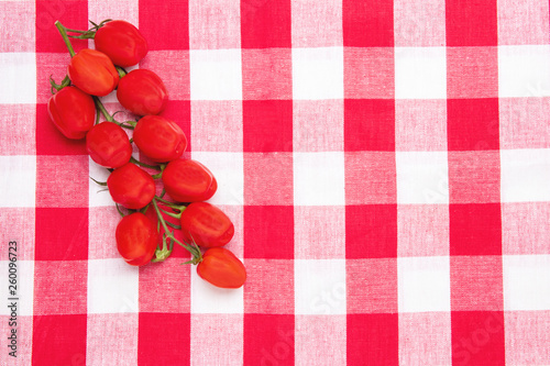 Healthy food background. Top view of fresh red cherry tomatoes on a red checkered napkin or towel. Place for your design. Concept health. photo