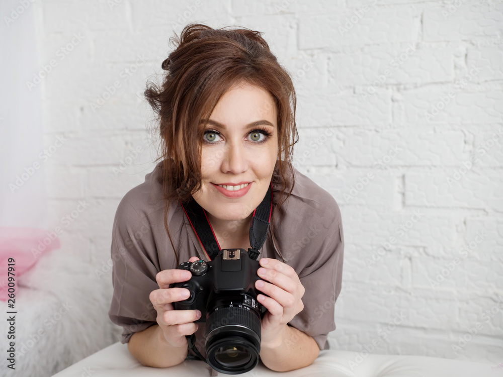 Portrait of a beautiful girl with a smile holding a camera indoors