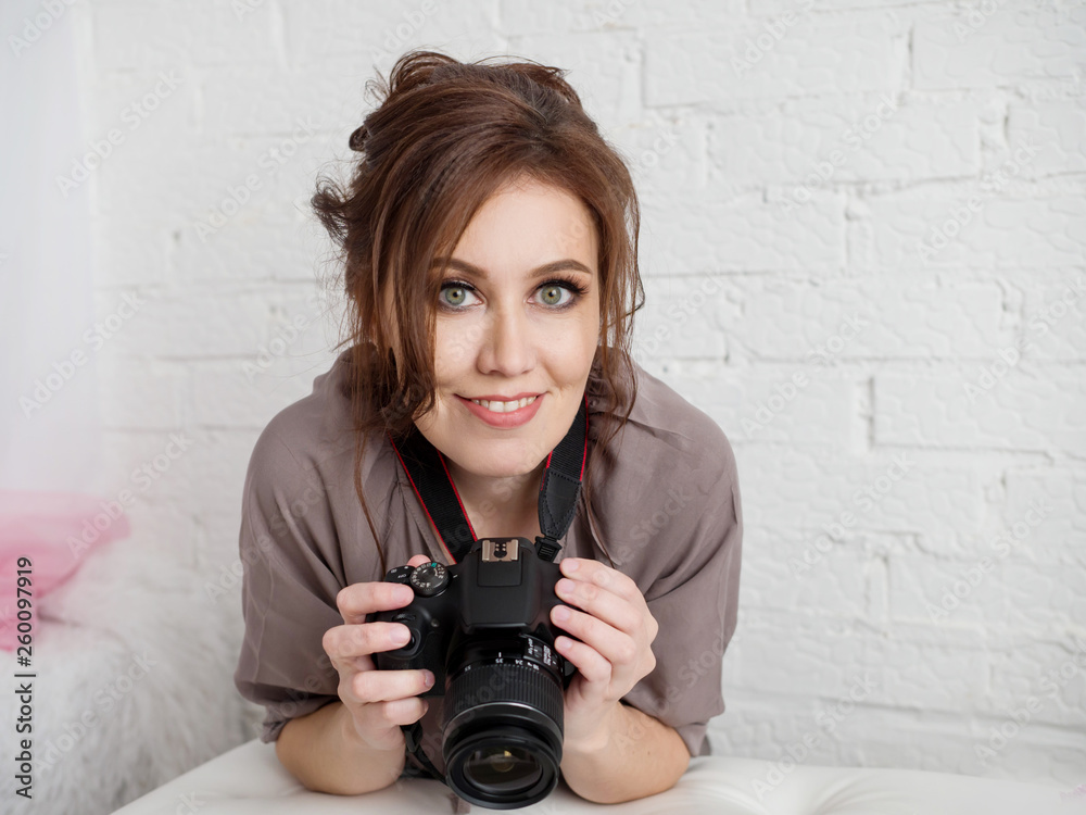 Portrait of a beautiful girl with a smile holding a camera indoors Portrait of a beautiful girl with a smile holding a camera indoors