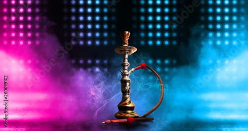 Hookah smoking on a dark abstract background. Background of empty scenes with neon lights and colored lights, reflection of night lights on wet asphalt