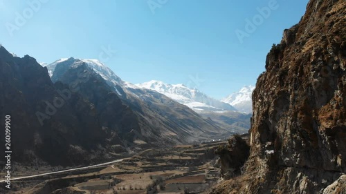 The ruins of ancient towers on a rock in the mountains of Upper Balkaria. Aerial view of the gorge with a dirt road and a mountain river in the mountains of the Caucasus. sunny day photo