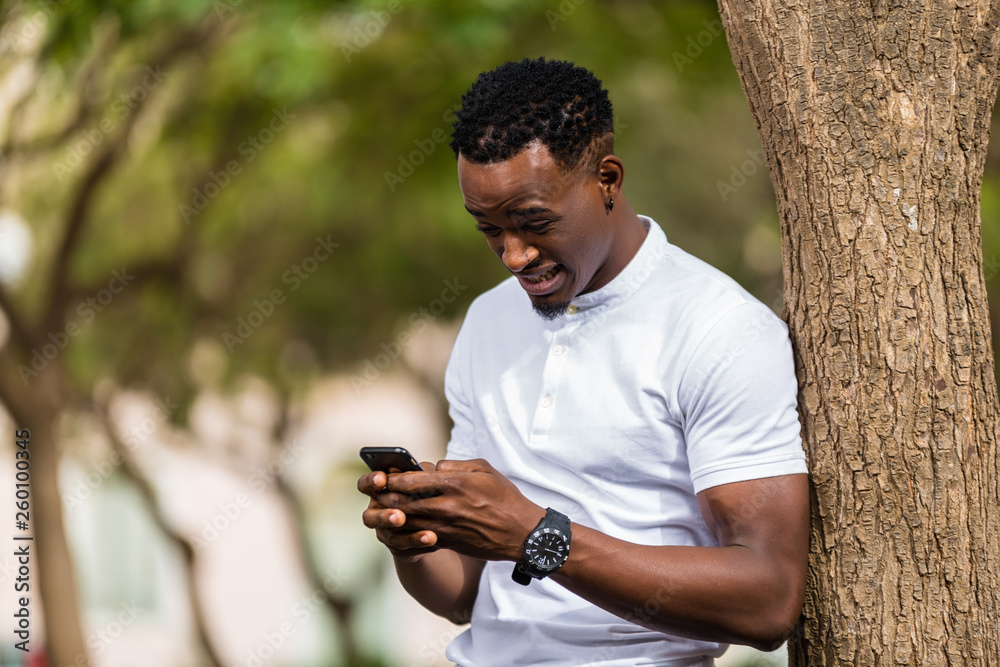 Outdoor portrait of a Young black African American men texting  on mobile phone
