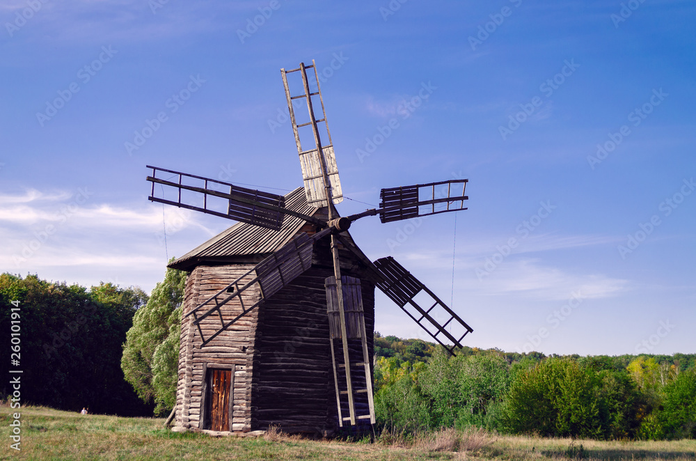 Ancient wooden mill on a green glade