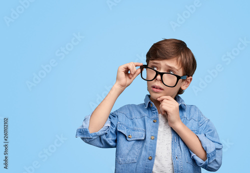 Pensive smart boy in eyeglasses looking away
