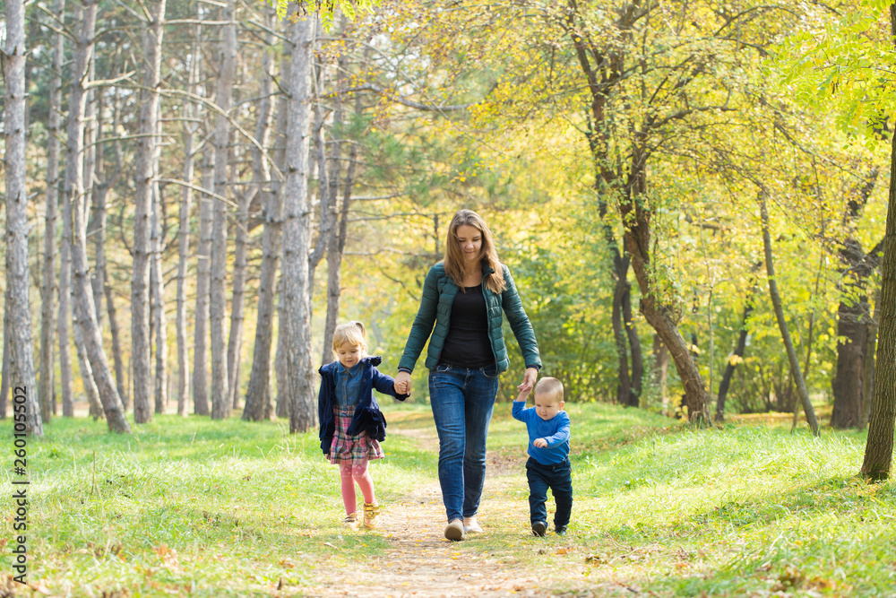 Mom, son and daughter walking in the park at sunset